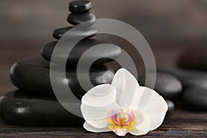 Stack of spa stones with beautiful orchid flower on blurred background