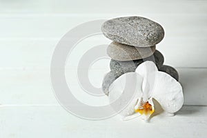 Stack of spa stones and beautiful orchid flower on white table