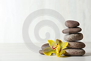 Stack of spa stones and flower on table against white background