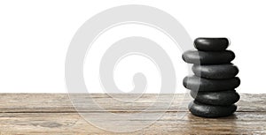 Stack of spa stones on wooden table against white background. Space for text