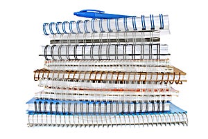 Stack of spiral notebooks with coil binding with a blue pen