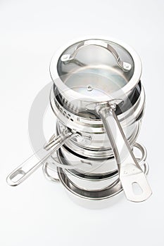 Stack of stainless saucepans on a gray background