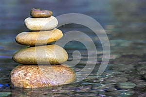 Stack of stones balancing on top in blue water of the river