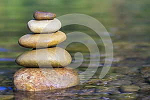 Stack of stones balancing on top in green water of the river