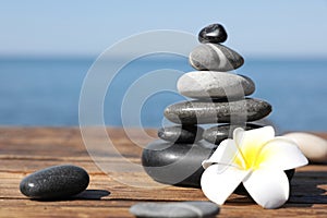 Stack of stones and flower on wooden pier, space for text. Zen concept