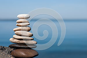 Stack of stones on rock near sea, space for text. Harmony and balance concept