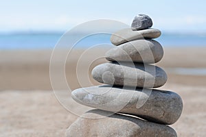 Stack of stones on sandy beach near sea, closeup. Space for text