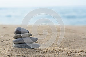 Stack of stones on sandy beach near sea, space for text