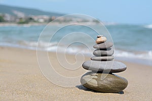 Stack of stones on sandy beach near sea, space for text