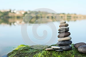 Stack of stones on seaweed near river, space for text. Harmony and balance concept