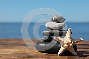 Stack of stones and starfish on wooden pier near sea. Zen concept