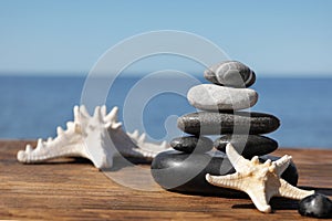 Stack of stones and starfishes on wooden pier near sea, Zen concept