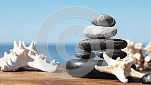 Stack of stones and starfishes on wooden pier near sea. Zen concept