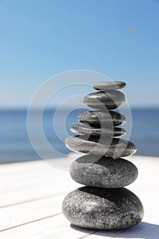 Stack of stones on wooden pier, space for text. Zen concept
