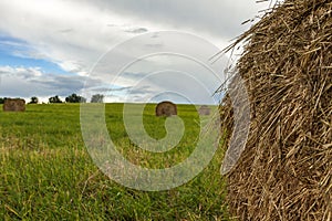 A stack of straw against the background of a field of blue sky and the rays of the sun