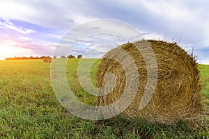 A stack of straw against the background of a field of blue sky and the rays of the sun