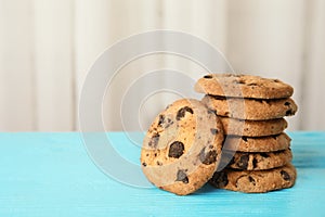 Stack of tasty chocolate chip cookies on wooden table.