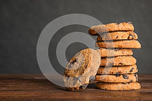 Stack of tasty chocolate chip cookies on wooden table.