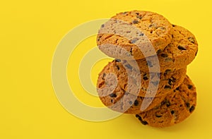 Stack of tasty chocolate chip cookies on yelllow background