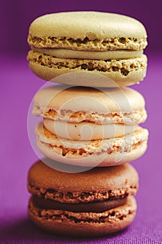 Stack of tasty macarons including vanilla, chocolate and matcha tea flavours.