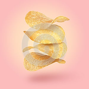 Stack of tasty potato chips falling on pink background