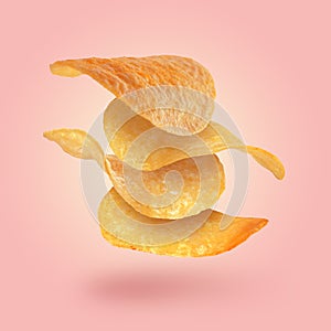 Stack of tasty potato chips falling on pink background