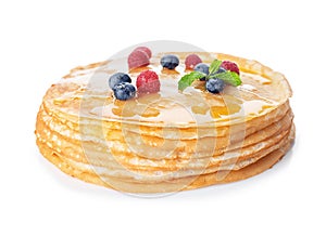 Stack of tasty thin pancakes with maple syrup and fresh berries