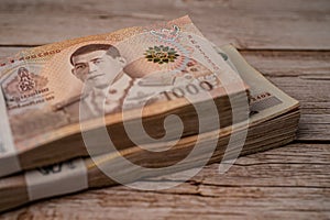 Stack of Thai baht banknotes on wooden background, business saving finance investment.