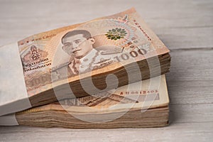 Stack of Thai baht banknotes on wooden background, business saving finance investment concept