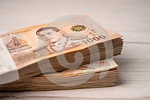 Stack of Thai baht banknotes on wooden background, business saving finance investment concept