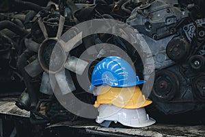 Stack of three colorful worker helmets at workplace manufacturing plant factory construction site building with many engine parts