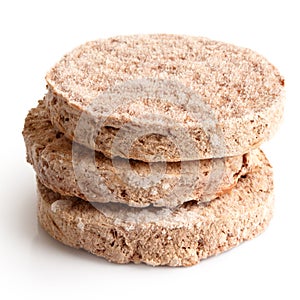 Stack of three frozen hamburger patties on white.