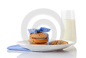 Stack of three homemade oatmeal cookies tied with blue ribbon in small white polka dots and bitten cookie on white ceramic plate o