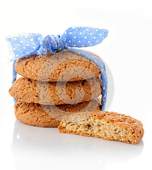 Stack of three homemade oatmeal cookies tied with blue ribbon in small white polka dots and half of cookie