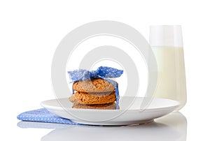 Stack of three homemade oatmeal cookies tied with blue ribbon in small white polka dots on white ceramic plate on matching blue na