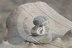 Stack of three stripy pebbles on a driftwood log