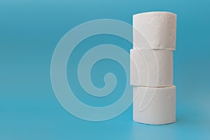 Stack of toilet paper rolls on blue background. Copy space