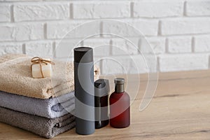 Stack of towels and man toiletries on wooden table.