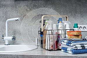 Stack of towels, sponges and various cleaning products on the kitchen table next to the sink