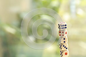 Stack tower of many small game dice isolated on a bright blurred background, group of objects, nobody. Probability and chance