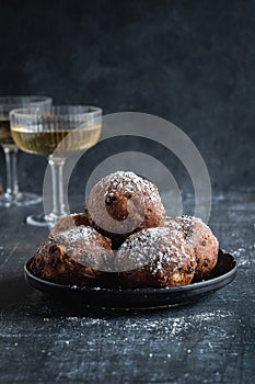 A stack of traditional oliebollen (translation: Dutch dough fritters) with a glass of champagne, black background