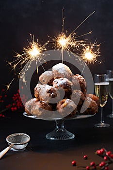 A stack of traditonal Dutch oliebollen (translation: deep fried dough balls) with sparkles and champagne