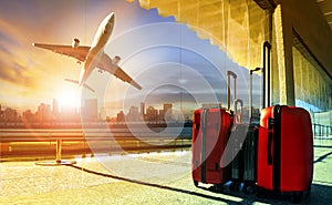 stack of traveling luggage in airport terminal and passenger plane flying over building in city