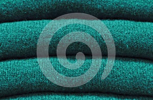 Stack of trend Quetzal Green woolen sweaters close-up, texture, background