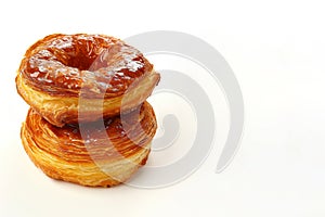 Stack of trendy delicious backed glassed dessert cronuts isolated on white background with copy