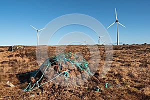 Stack of turf in a bog next to wind farm turbine. Clean new and dirty old source of energy. Natural and artificial product in