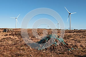 Stack of turf in a bog next to wind farm turbine. Clean new and dirty old source of energy. Natural and artificial product in