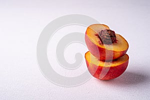 Stack of two slice of peach nectarine fruit with seed on white background, copy space, angle view