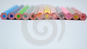 Stack of various colored wood pencil crayons scattered across a white background