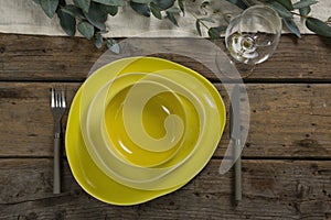 Stack of various dinnerware with cutlery and empty glass